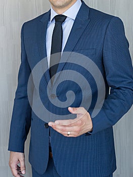 Torso of a businessman standing, making italian hand gesture, wearing navy blue suit.