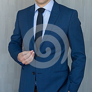 Torso of a businessman standing, making italian hand gesture, wearing navy blue suit.
