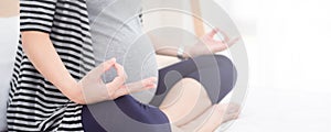 Torso close-up of pregnant woman. Pregnant fitness woman sitting in yoga crossed-leg pose . Pregnancy Yoga