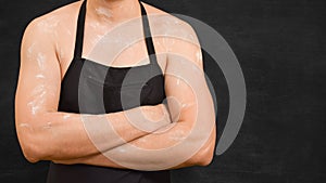 Torso of a male chef in an apron on a black background.