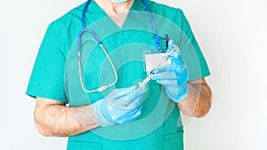 Torso of a male doctor close-up on a white background. A doctor in a protective blue suit with a stethoscope holds a syringe and