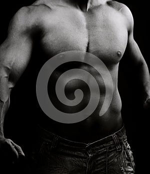 Torso of muscular shirtless man in the dark