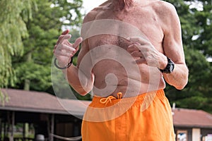 Torso view of older man bare chested in yellow bathing suit wear