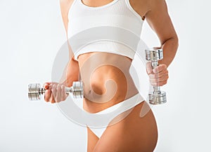 Torso of a young fit woman lifting dumbbells