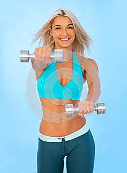 Torso of a young fit woman lifting dumbbells