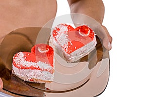 Torso of young handsome guy with two heart-shaped cakes on a plate. portrait of romantic man with valentine on