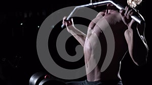 Torso of young man doing lats pulldown exercises to front in gym