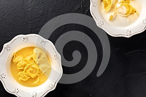 Tortellini with broth and cream sauce, Italian food on a black background with copy space