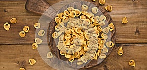 Tortellini mignon on a wooden board with basil and parmesan. Specialties of the cuisine from Bologna and Emilia Romagna