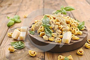 Tortellini mignon on a wooden board with basil and parmesan. Specialties of the cuisine from Bologna and Emilia Romagna