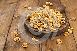 Tortellini mignon on a wooden board . Specialties of the cuisine from Bologna and Emilia Romagna