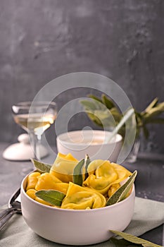 Tortellini with sage, ricotta and spinach. Italian pasta and white wine. Traditional Bologna cuisine, Emilia Romagna