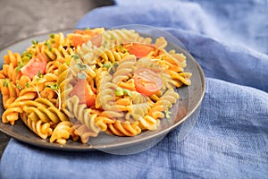 Tortiglioni semolina pasta with tomato and microgreen sprouts on a black concrete background. Side view, selective focus