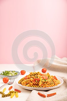 Tortiglioni semolina pasta with tomato and microgreen sprouts on a white and pink background. Side view, copy space