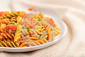 Tortiglioni semolina pasta with tomato and microgreen sprouts on a white wooden background. Side view, selective focus