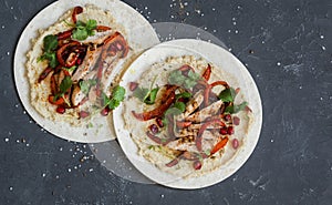 Tortilla with hummus, baked chicken and sweet pepper. On a dark background