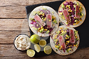 Tortilla with tuna steak, sesame and fresh vegetables close-up.