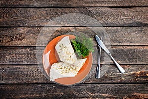 Tortilla wrap with chicken breast and vegetables on a ceramic plate. Served with cutlery on a wooden background.