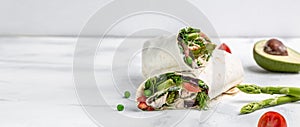 Tortilla wrap with fried chicken meat and vegetables asparagus, avocado, tomatoes, peas, cheese and tartar sauce on
