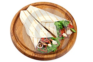 Tortilla wrap with fried chicken meat and vegetables on wooden board isolated on white background