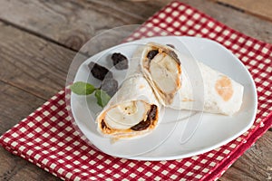 Tortilla wrap with peanut butter, raisin and banana on whi