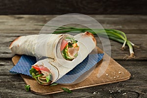 Tortilla wrap or wrap sandwich with ham and vegetables close up. Roll sandwich with meat and green salad