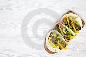 Tortilla wraps with grilled beef meat, salad, parsley, tomato, pepper on wooden board.