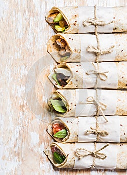 Tortilla wraps with various fillings on shabby white wooden board