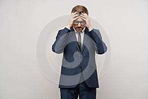 Tortured businessman trying make decision, thinking hard about problems troubles on gray background.