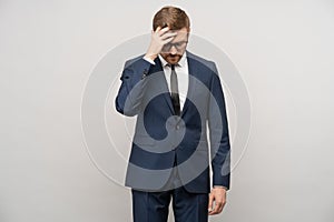 Tortured businessman trying make decision, thinking hard about problems troubles on gray background.