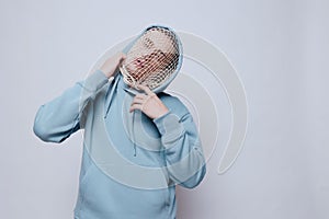 tortured, suffering from problems, a man with a mesh on his face stands in a light blue hoodie on a light background and