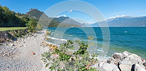 Toscolano beach, lake shore Gardasee, with rocks and gravel, mountain view