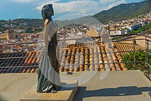 TOSSA DE MAR, SPAIN: Sculpture of a woman. The city walls of the old fortress of Tossa de Mar on a sunny day