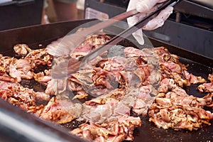 Tossing meat slices on a flat top grill