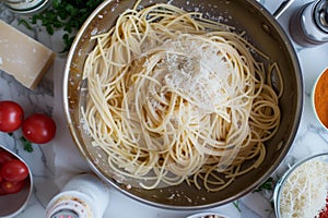 tossing spaghetti in a pan with separate ingredients positioned around it