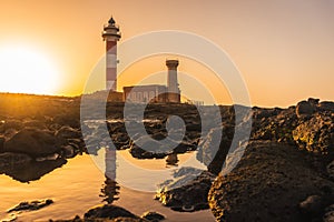 Toston Lighthouse with its reflection in the water at sunset in Punta Ballena, Spain