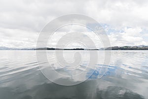 Tota lake, calm landscape, cloudy sky reflected in the water surface photo