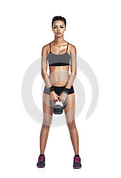 Total body perfection. Studio portrait of a fit young woman in sportswear lifting a kettlebell isolated on white.