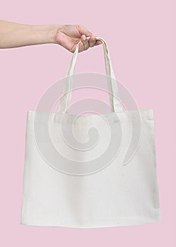 Tote bag canvas white cotton fabric cloth for eco shoulder shopping sack mockup blank template isolated on pastel pink background