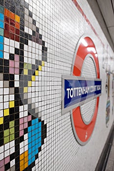 Tottenham Court Road Underground Station, London, UK showing mosaic tiles by Eduardo Paolozzi and the TFL Roundel in soft focus.