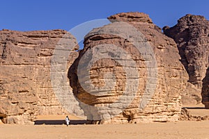 Touareg walking between massive rocks in the sahara desert of Algeria