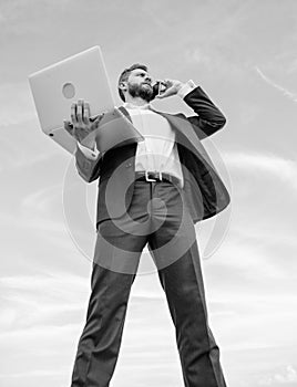 Always in touch. Man well groomed businessman holds laptop while speak phone blue sky background. Guy formal suit modern