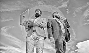Always in touch. Men well groomed businessman holds laptop partner speak phone blue sky background. Communicating skill