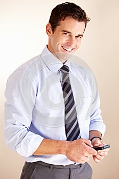 Always in touch - Modern technology. Smiling young businessman sending a text message.