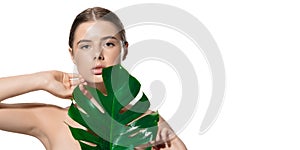 Touch. Portrait of beautiful young woman with green leaf on her face over white background. Cosmetics and makeup