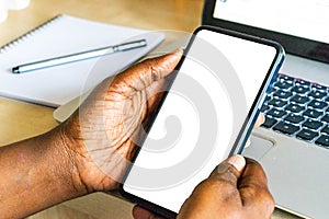 Touch screen mobile phone, in African woman`s hand. Black Female holding smart phone on green outdoor background with blank copy s