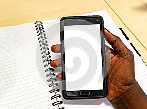 Touch screen mobile phone, in African woman`s hand. Black Female in office holding smartphone using electronic gadget notebook