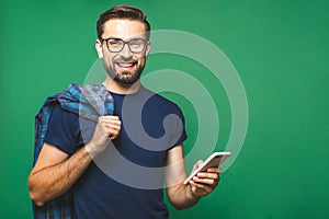 Always in touch. Smiling young man holding smart phone and looking at it. Portrait of a happy man using mobile phone isolated over