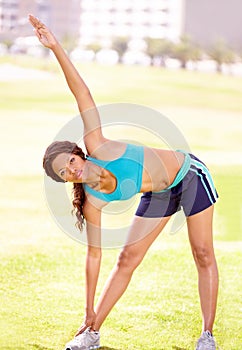 Touch your toes and reach to the sky. A fit young woman warming up with some stretches.