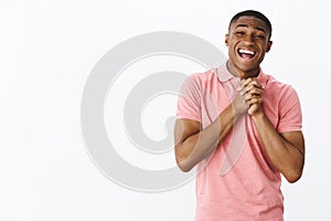 Touched sweet and cute handsome young african american gay man in pink polo shirt holding hands together over chest